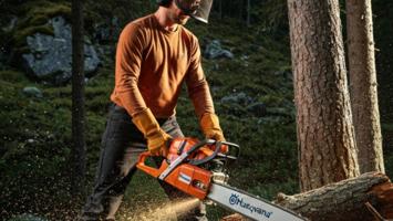 Person bruker Husqvarna motorsag for vedhogging i norsk skog